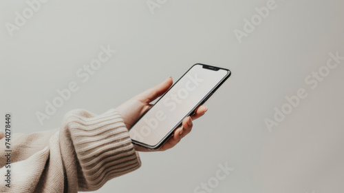 A hand is holding a smartphone with a blank screen against a white background, offering a clear view for placing a digital interface or mobile app demonstration.