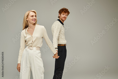 Valokuva happy blonde woman and redhead man in trendy casual clothes holding hands on gre