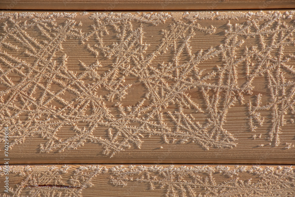 Brown wood texture with white frost patterns. Winter background.