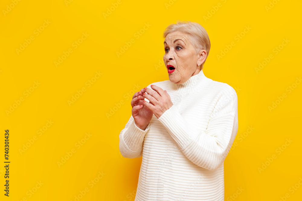 frightened old grandmother in white sweater is surprised and worried on yellow isolated background, shocked elderly woman pensioner looks away in amazement frightened old grandmother in white sweater is surprised and worried on yellow isolated background, shocked elderly woman pensioner looks away in amazement
