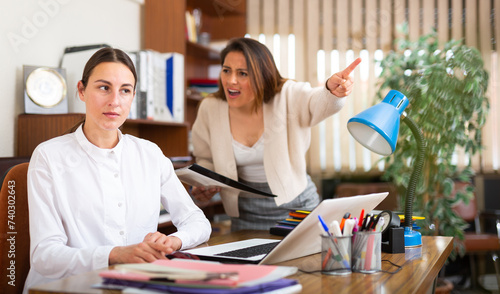 Outraged business woman expressing dissatisfaction with work of confused secretary in office photo