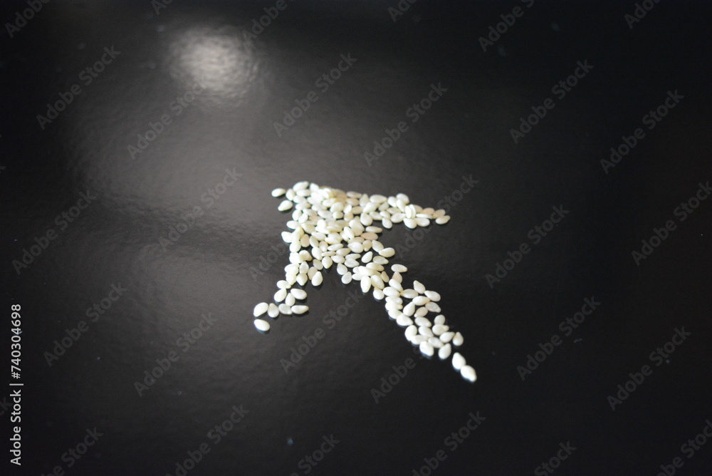 Style and food, white, small sesame seeds arranged on a black glossy background.