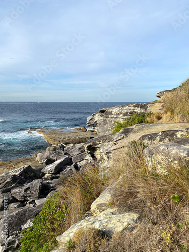 The coast of the sea. Mountains cliff in the ocean. View of the rocky coast of island  Australia. Waves curling on the rocky shore.