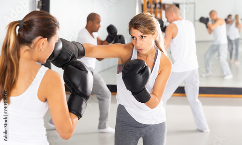 Sports young woman mastering self defense techniques, practicing punches at boxing gym.