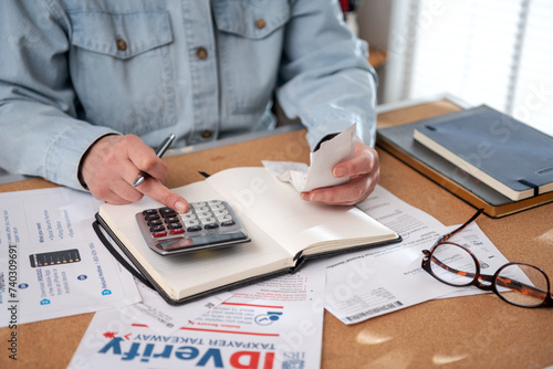 Woman work with financial papers at home count on calculator before paying taxes receipts . woman planning budget  for saving money photo