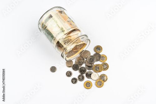 Polish zloty banknotes and coins in glass jar white background. Saving money concept.