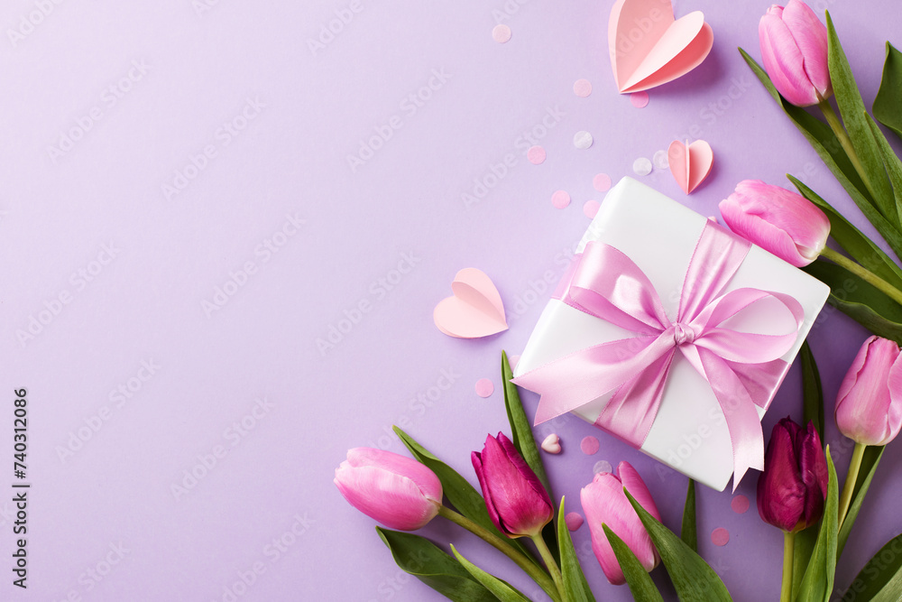 Elegance in gifting: delighting the special women in our lives. Top view shot of tulips, gift box, scattered paper hearts on lavender background with space for expressions of love or marketing slogan Elegance in gifting: delighting the special women in our lives. Top view shot of tulips, gift box, scattered paper hearts on lavender background with space for expressions of love or marketing slogan