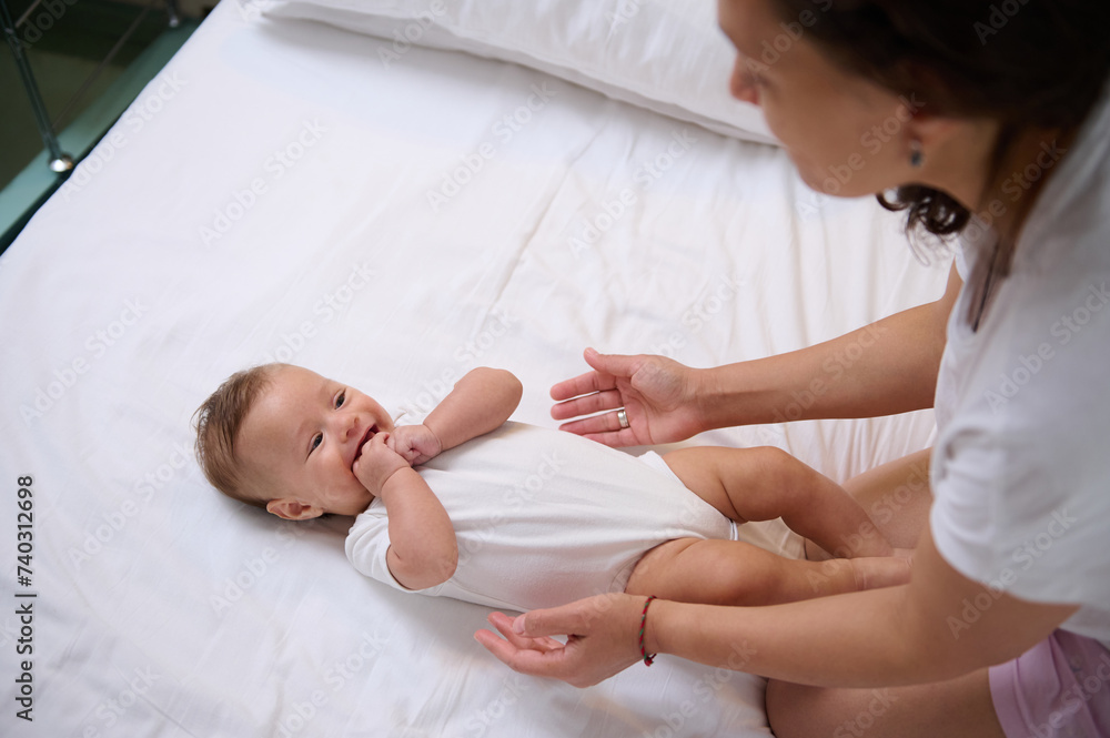Adorable baby boy laughing and smiling looking at his mom cuddling him. Babyhood and infancy. Maternity and baby care Adorable baby boy laughing and smiling looking at his mom cuddling him. Babyhood and infancy. Maternity and baby care