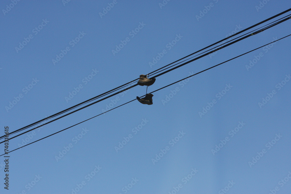 Boots dangling on power lines, capturing urban essence with an unexpected twist. A touch of rebellion in the cityscape.
