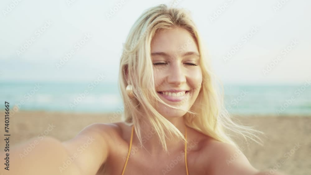 Happy young woman with camera in hand takes a selfie with her mobile phone smiling while enjoying a sunset on the beach in summer. POV camera point of view- Concept of summer holidays Happy young woman with camera in hand takes a selfie with her mobile phone smiling while enjoying a sunset on the beach in summer. POV camera point of view- Concept of summer holidays