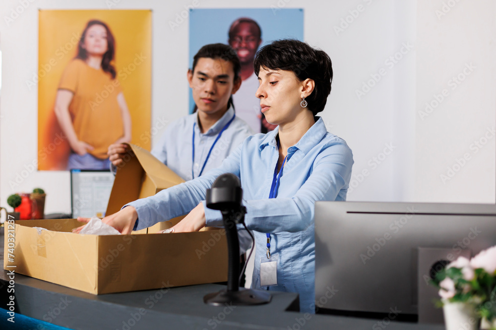 Formal workers preparing clients orders, working with packages in modern boutique. Employees putting fashionable clothes in cardboard boxes, discussing shipping detalis at counter desk Formal workers preparing clients orders, working with packages in modern boutique. Employees putting fashionable clothes in cardboard boxes, discussing shipping detalis at counter desk