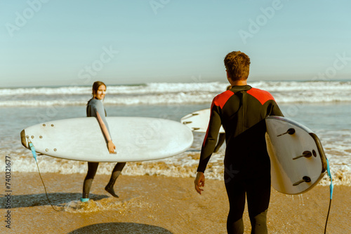 Group of friends with surfboards entering towards ocean for surfing on waves. High quality photo