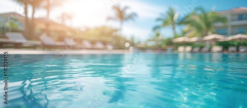 Tropical paradise with a crystal clear pool surrounded by lush palm trees under the blue sky