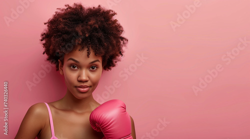 Breast cancer awareness month concept, Afro girl with boxing glove on pink background, copy space text © Enrique