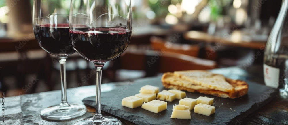 Elegant glass of red wine with assorted gourmet cheese plate on wooden table