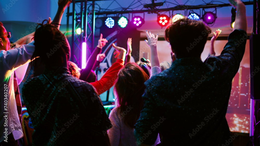 Cheerful adults having fun with DJ music on panel station, dancing under disco lights on dance floor. Young crowd of friends partying and clubbing with modern funky beats. Handheld shot. Cheerful adults having fun with DJ music on panel station, dancing under disco lights on dance floor. Young crowd of friends partying and clubbing with modern funky beats. Handheld shot.