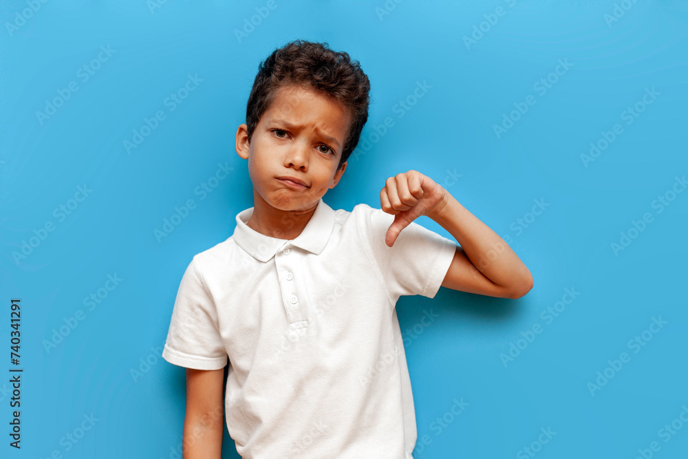 dissatisfied african american boy in white polo showing dislike on blue isolated background dissatisfied african american boy in white polo showing dislike on blue isolated background