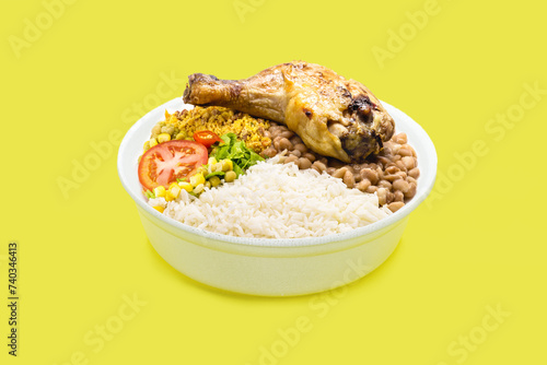 marmita or marmitex, Brazilian home-delivered lunch meal, with rice, chicken thigh, farofa and salad, beans, copy space, yellow background