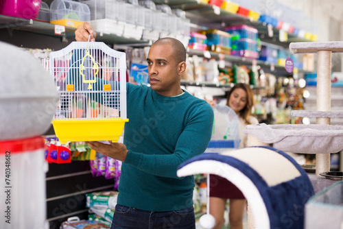 Portrait of male shopper looking for new bird cage in pet shop