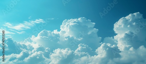 A natural landscape with an electric blue sky filled with fluffy white cumulus clouds creating a picturesque horizon. A meteorological phenomenon of wind and clouds