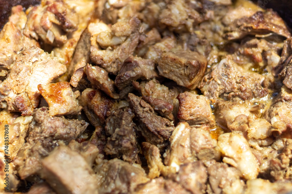 Close up of meat being cooked in a cauldron. Selective focus.