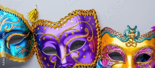 Three different colored Mardi Gras masks are hanging on a white wall, showcasing the festive and vibrant celebration of Mardi Gras.