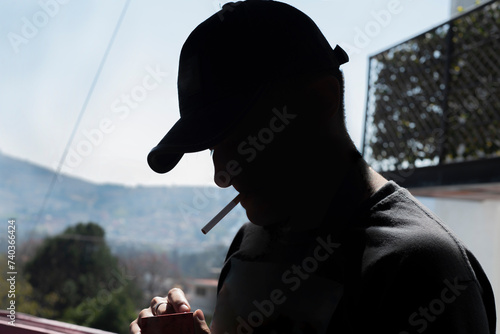 Hombre fumador, con la nariz chueca, a contra luz. photo