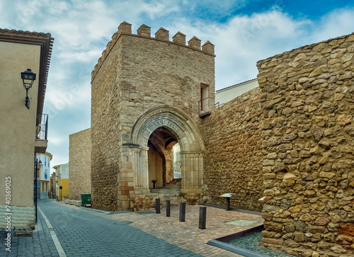 Panorama street view of San Gines gate in Lorca the only surviving medieval entrance through the city walls with crenellations at the top and archway photo