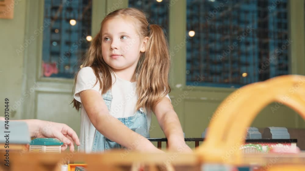 Multicultural girl playing toy to improve and develop creativity. Diverse student sitting while holding car model at playroom in elementary school at break time. Creative activity concept. Erudition.