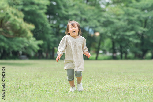芝生の公園で遊ぶ女の子・子供・キッズ（はしゃぐ・笑顔・成長）
