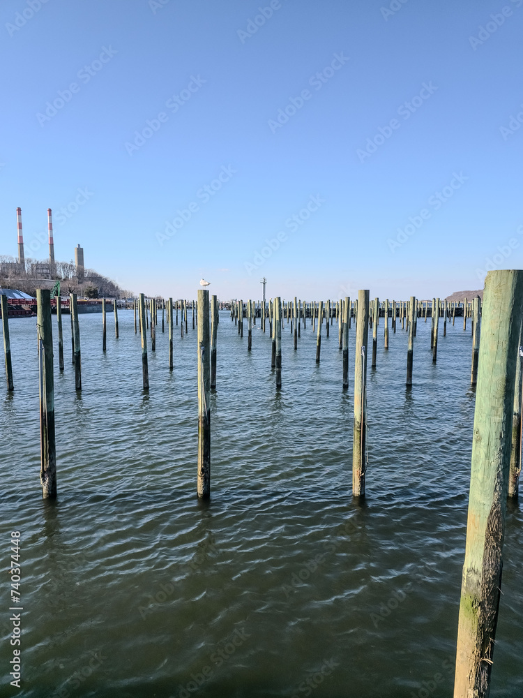 Tranquil marina scene with old wooden pier pillars standing in calm waters under a clear blue sky, evoking peace in Long Island Tranquil marina scene with old wooden pier pillars standing in calm waters under a clear blue sky, evoking peace in Long Island
