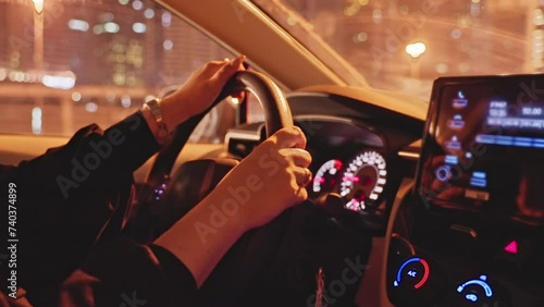 Successful woman driving premium class car in night city, hands close-up.