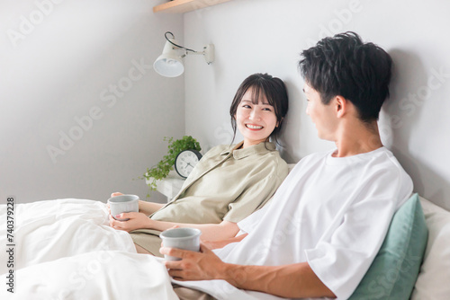 寝室・ベッドルームでホットドリンク・コーヒーを飲むアジア人夫婦・カップル・恋人・家族
 photo