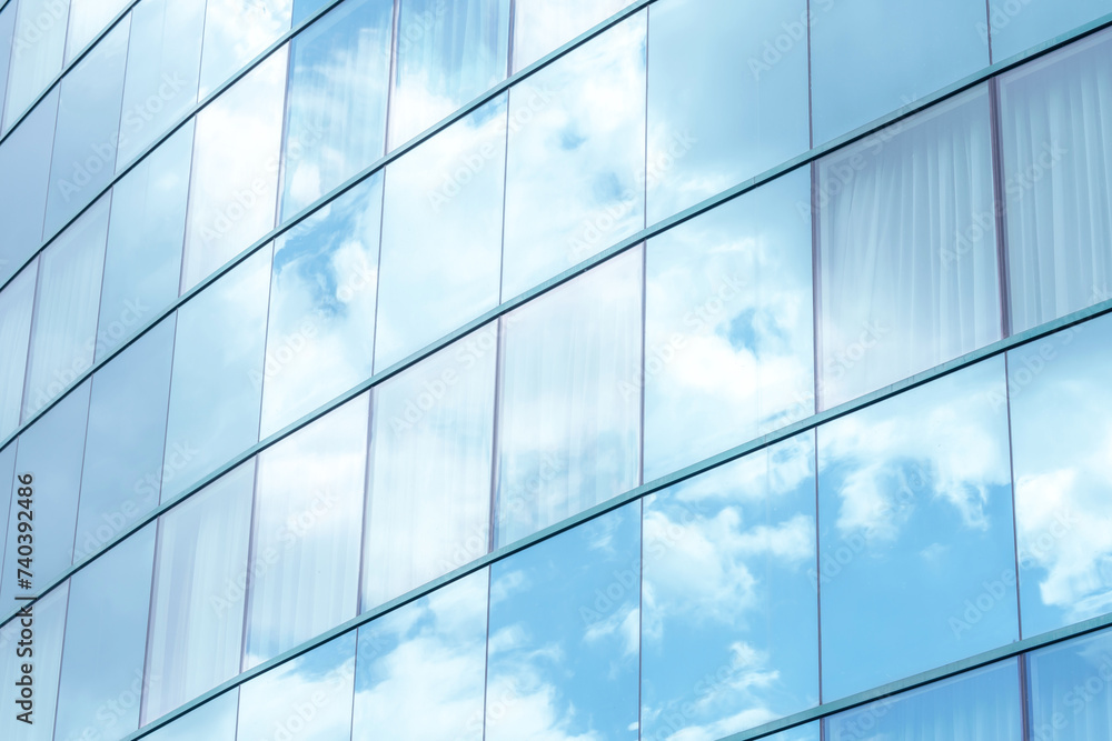 Contemporary office building with reflective glass panels that mirror blue sky and white clouds, building blending with the sky. Modern minimalistic corporate architecture, simple background texture Contemporary office building with reflective glass panels that mirror blue sky and white clouds, building blending with the sky. Modern minimalistic corporate architecture, simple background texture
