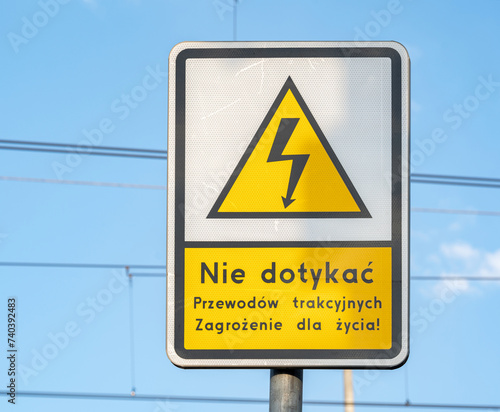 Caution sign with a warning message in Polish against touching overhead electrical wiring indicating a life-threatening hazard concept. Universal electric shock lighting symbol, nobody, front view