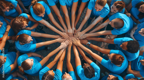 A group of people wearing blue shirts and forming a human ribbon