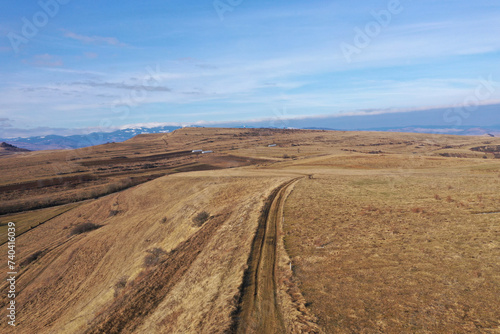  Flying above a countryside dirt road and meadow  aerial view
