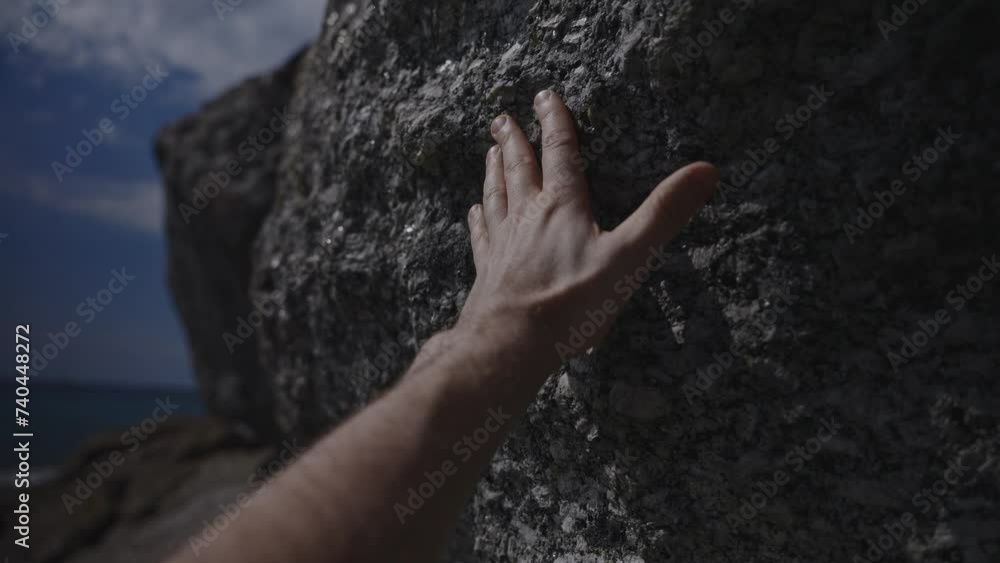 A person is touching a large rock with their hand