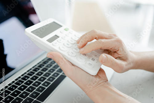 Business woman using a calculator to calculate the numbers on his desk in a office.