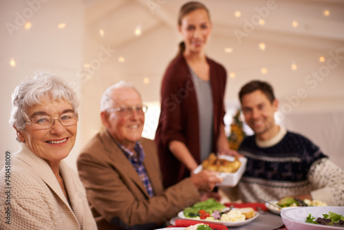Grandmother, portrait and family at dinner on Christmas, together with food and celebration in home. Happy, event and people smile with lunch, dish and relax on holiday at table with grandparents