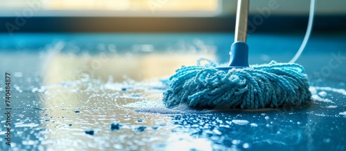 Gleaming blue mop cleaning up water spill on floor, household cleaning tool photo