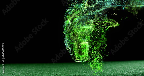 Image of glowing green particles moving over rugby ball on pitch