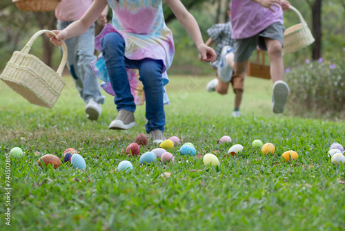 Group of children happily runs around pick up Easter eggs in the park, Easter egg hunt concept, selective focus
