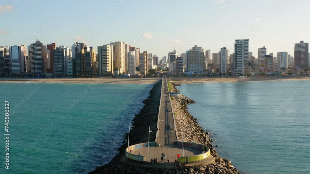 Aerial view of footbridge with people walking around, from the sea to the city with many buildings in the background, Fortaleza, Ceara, Brazil
