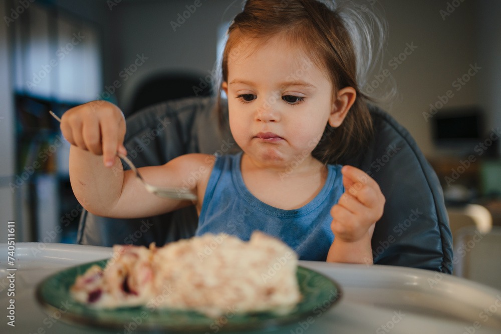 Caucasian little girl concentrated while having breakfast with family at home. Caucasian little girl concentrated while having breakfast with family at home.
