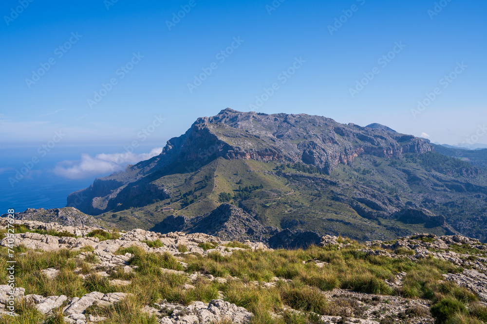 Fototapeta premium Amazing landscapes of Mallorca. The mountains are covered with greenery, the sea is blue and transparent. Sunny day, clouds over a rocky ridge. Mallorca, Spain, Balearic Islands