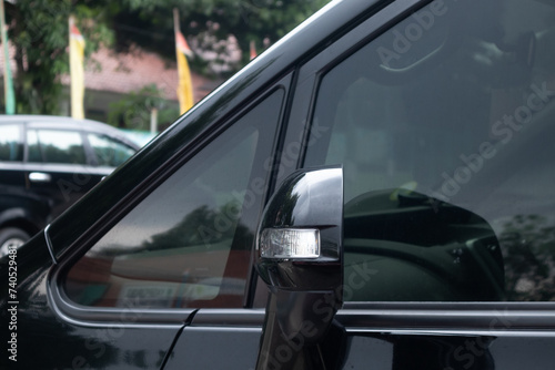 Side view mirror with turn signal lamp on a black car © fadfebrian