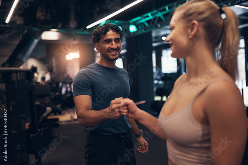 Smiling people fist-bumping after a gym workout together photo