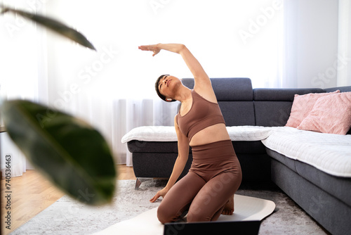 Beautiful fit woman practicing yoga exercise at home.
