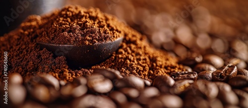 A pile of coffee beans with a spoon in it, a staple food ingredient for various cuisine recipes. The macro photography captures the rich aroma of the beans placed on a wooden surface